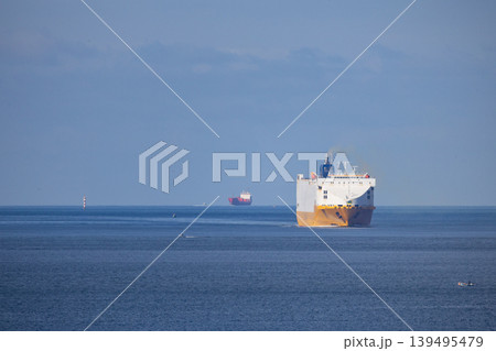 Large cargo ships navigate on calm waters near the coast on a sunny day in the afternoon Large cargo ships navigate on calm waters near the coast on a sunny day in the afternoon 139495479