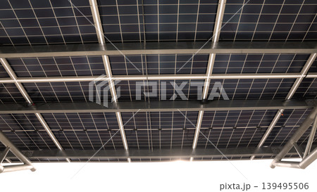 Solar panel car park roof. Low angle shot of Solar panel carport roof with steel structure generating clean renewable energy. Sustainable parking canopy with photovoltaic cells for eco power energy. Solar panel car park roof. Low angle shot of Solar panel carport roof with steel structure generating clean renewable energy. Sustainable parking canopy with photovoltaic cells for eco power energy. 139495506