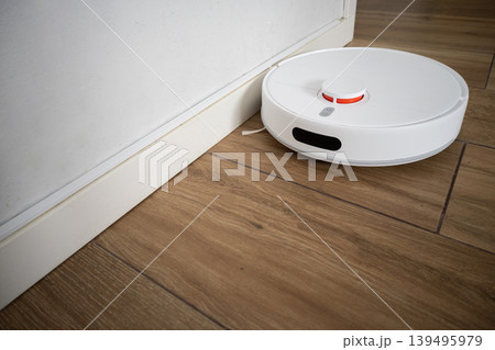 Robot vacuum cleaner cleaning wooden floor in modern living room 139495979