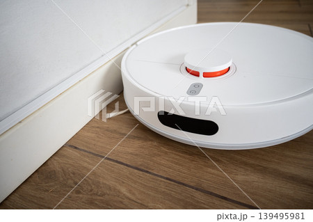 Robot vacuum cleaner cleaning wooden floor in modern living room 139495981
