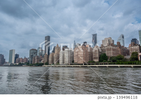New york, usa august 17,2024. Manhattan skyline seen across the east river on a cloudy day, featuring the united nations headquarters and urban architecture New york, usa august 17,2024. Manhattan skyline seen across the east river on a cloudy day, featuring the united nations headquarters and urban architecture 139496118