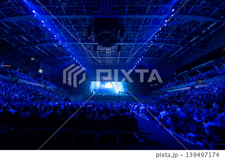 Concert audience in indoor arena under dramatic blue stage lights and live performance production 139497174