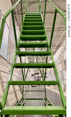 Bright green metal staircase in store interior, low angle perspective with symmetrical lines. Bright green metal staircase in store interior, low angle perspective with symmetrical lines. 139497874