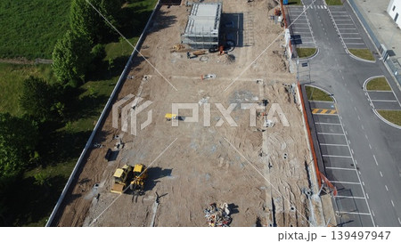 Aerial view of a construction site with heavy machinery and building foundations under development. Aerial view of a construction site with heavy machinery and building foundations under development. 139497947