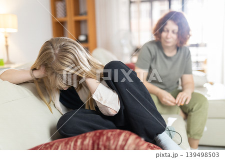 Frustrated young girl ignoring sad mother at home Frustrated young girl ignoring sad mother at home 139498503