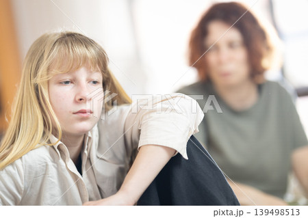 Teenager feeling sad with parent in background Teenager feeling sad with parent in background 139498513