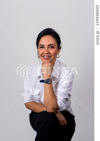 A woman wearing a white shirt and black pants is smiling and holding her wrist 139498605