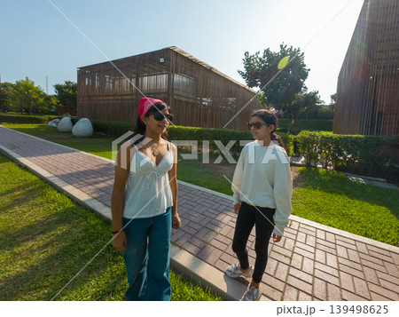 Two young women are walking down a brick path in a park 139498625