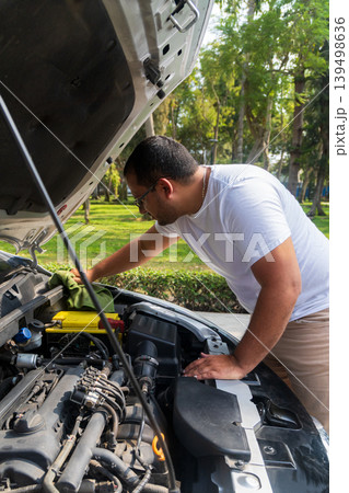 A man is working on a car engine in a park A man is working on a car engine in a park 139498636
