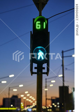 Traffic light shining bright against a twilight sky in a bustling city 139499804