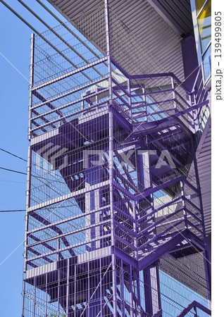 Unique purple stairwell stands out against a clear blue sky in an urban setting Unique purple stairwell stands out against a clear blue sky in an urban setting 139499805
