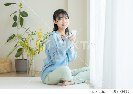 部屋でスマホを使う若い女性 部屋でスマホを使う若い女性 139500497