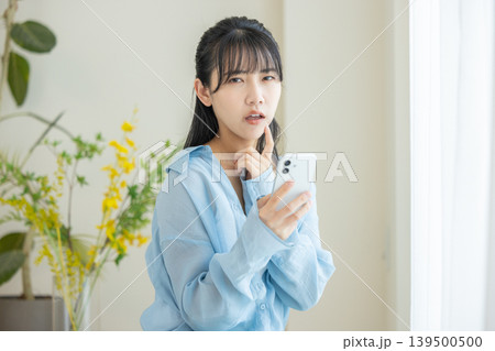 スマホを見て悩む女性 139500500