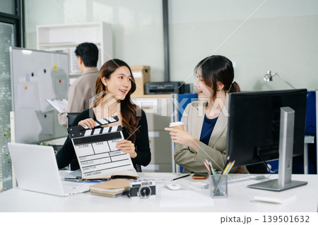 Creative team planning video production in modern office, using clapperboard, laptop and notebook. Business, marketing, content creation Creative team planning video production in modern office, using clapperboard, laptop and notebook. Business, marketing, content creation 139501632