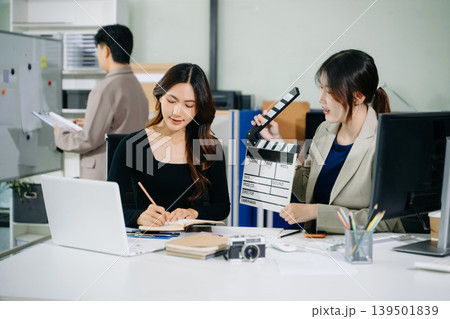 Creative team planning video production in modern office, using clapperboard, laptop and notebook. Business, marketing, content creation 139501839