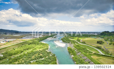 曇天の五月、雨が降り出しそうな黒部川扇状地と愛本橋や公園などの周辺の施設の様子 139502314