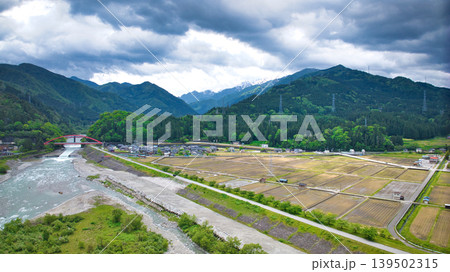 曇天の五月、雨が降り出しそうな黒部川扇状地と愛本橋や公園などの周辺の施設の様子 139502315