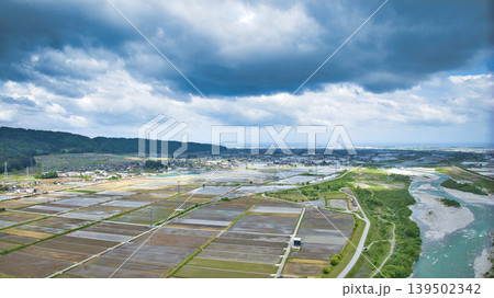 曇天の五月、雨が降り出しそうな黒部川扇状地と愛本橋や公園などの周辺の施設の様子 139502342