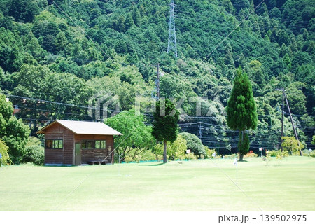 新緑の山々と芝生の広場にある木造小屋 新緑の山々と芝生の広場にある木造小屋 139502975