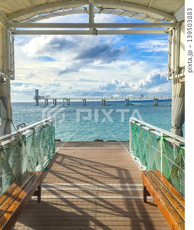 Ocean pier in Japan Okinawa with benches and blue sky, leading to a distant structure over the water 139503883
