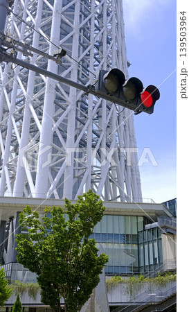 Red traffic light against a modern white lattice tower and blue sky 139503964