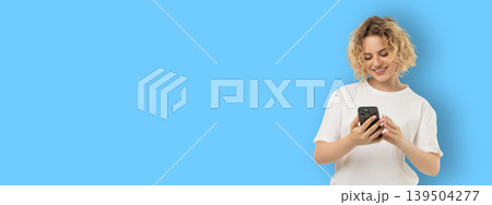 Woman smiles while using smartphone in a bright space Woman smiles while using smartphone in a bright space 139504277