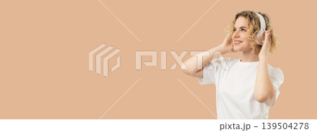 Woman smiles while wearing headphones and enjoying music Woman smiles while wearing headphones and enjoying music 139504278