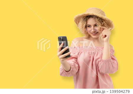 Woman holds smartphone with a smile while wearing a hat Woman holds smartphone with a smile while wearing a hat 139504279
