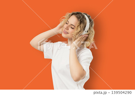 Woman listens to music while wearing headphones and smiling 139504290