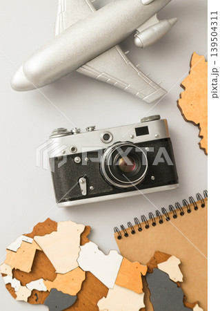 Camera and airplane model near travel-themed items on table 139504311