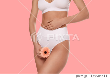 Woman confidently enjoys body care while holding a flower 139504411