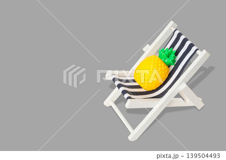 Pineapple sits on a small striped chair in a simple spot Pineapple sits on a small striped chair in a simple spot 139504493