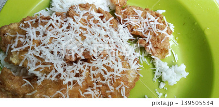 Fried omelette with grated cheese on white rice on a green plate. 139505534