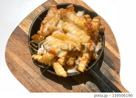 Delicious cheesy fries served in a cast iron skillet on wooden board 139506190