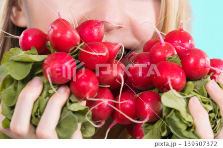 woman holding radish close to face woman holding radish close to face 139507372