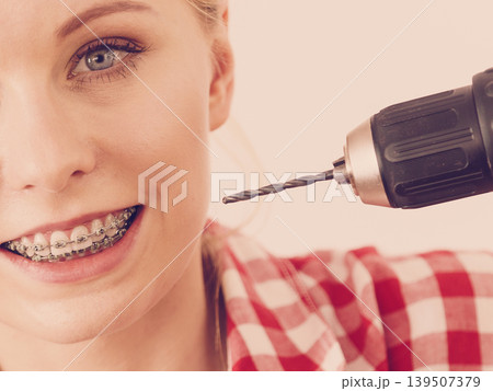 Woman with braces using drill on her teeth 139507379