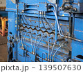 Close-up of a blue industrial metal leveler machine with a complex hydraulic system of pipes and valves. Heavy-duty manufacturing equipment 139507630