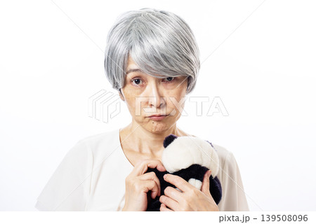 パンダのぬいぐるみを抱きしめて寂しそうな表情のシニア女性 139508096