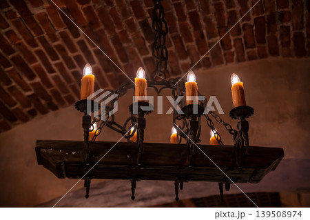 Antique iron chandelier with hanging candles on birck ceiling 139508974