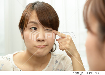 鏡を見て目を気にする女性 139509319