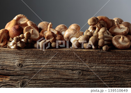 Fresh shiitake, champignon, and shimeji mushrooms on an old wooden table. 139510649