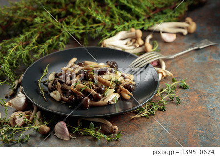 Fried shimeji mushrooms with thyme and garlic on a black plate. Fried shimeji mushrooms with thyme and garlic on a black plate. 139510674