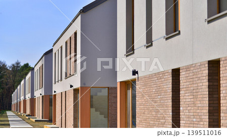 Terraced family homes in newly developed housing estate. The real estate market in the suburbs. New single family houses in a new development area. Residential homes with modern facade.  139511016