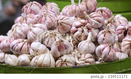 Fresh garlic bulbs piled in a green bowl 139511171