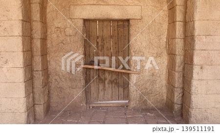 Weathered wooden door set in rough stone wall 139511191