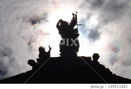 Silhouette of Saint James the Moor-slayer against the sun of a statue swanging the sword and carrying a banner with the Christian cross. 139511881