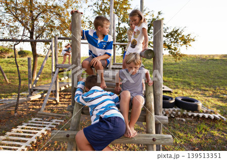 Children, friends and playing at park together on jungle gym for fun weekend, holiday or summer break in nature. Group of young kids or teens enjoying day at outdoor playground for game or activity Children, friends and playing at park together on jungle gym for fun weekend, holiday or summer break in nature. Group of young kids or teens enjoying day at outdoor playground for game or activity 139513351