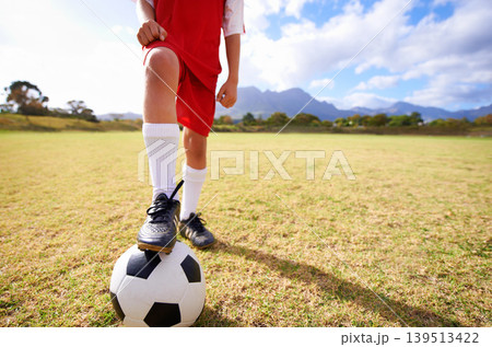 Child, soccer ball and legs on green grass for sports, training or practice with clouds and blue sky. Closeup of football player with foot ready for kick off, game or match on outdoor field in nature Child, soccer ball and legs on green grass for sports, training or practice with clouds and blue sky. Closeup of football player with foot ready for kick off, game or match on outdoor field in nature 139513422