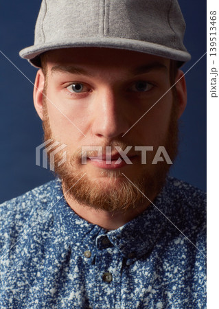 Man, fashion and face with hat in a studio, denim and trendy isolated on blue background. Irish model with hipster beard, ginger and serious in portrait, stylish and fashionable shirt in headshot 139513468
