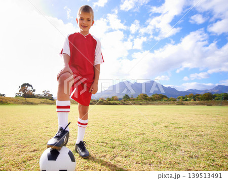 Happy child, soccer ball and sports on green grass for training or practice with clouds and blue sky. Portrait of young football player smile ready for kick off game, match or outdoor field in nature 139513491
